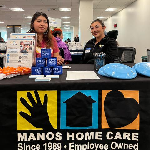 two people at a Manos booth at a career fair