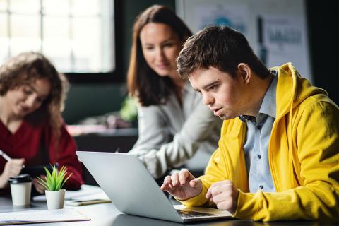 caregivers showing young man how to work on a computer.